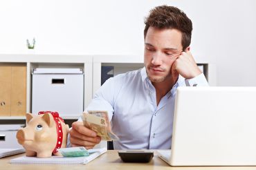 © Robert Kneschke - stock.adobe.com Foto: Mann mit Taschenrechner und Bargeld