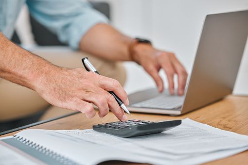 Foto: Männerhände auf PC und Taschenrechner